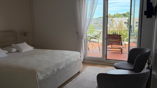 Ein Schlafzimmer mit Bett, Stuhl und einem Balkon mit Tisch und Stuhl.