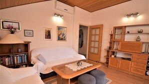 Una sala de estar acogedora con un sofá, una mesita de centro, una estantería y un armario de madera.