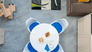 Une table ronde avec un plateau blanc et des touches de bleu, entourée d’une chaise bleue rembourrée.