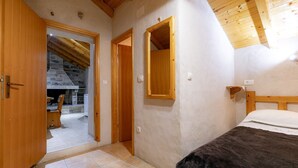 A bedroom with a wooden bed, a wooden door, and a stone wall. - Stone House Harmony - One Bedroom Apartment with Patio and Garden View ( 1 ) (Zrnovo)