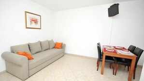 Una sala de estar con sofá y una mesa de comedor lista para cuatro personas.