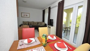 Un área de comedor con una mesa dispuesta para dos personas, un jugo y un sofá al fondo.