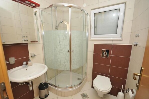 Un baño con ducha de vidrio, lavamanos e inodoro.