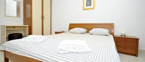 Un dormitorio con cama, armario, mesita de noche y espejo.