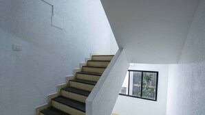 A staircase with a white wall and a window. - Treebo Royal Comfort Atithi (Pune)