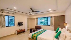 A hotel room with a bed, a desk, a chair, a TV, and a wardrobe. - Treebo Royal Comfort Atithi (Pune)
