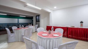 A conference room with round tables, white chairs, and a red tablecloth-covered table. - Treebo Royal Comfort Atithi (Pune)