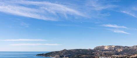 A coastal town with a clear view of the sea, a prominent hill, and a small island.