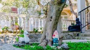Ein Garten mit Baum, einer Schwanstatue und einer Statue eines Mannes, der ein Kind hält.