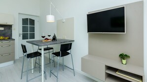 A modern kitchen with a dining area, a flat-screen TV mounted on the wall, and a small potted plant on the counter. - Villa Panorama Dubrovnik (A3) - Comfort One Bedroom Apartment with Balcony and sea View (Mlini)