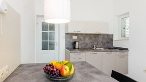 Una cocina moderna con encimera gris, una cafetera y un frutero.