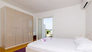 A bedroom with a bed, a wardrobe, a purple rug, and a view of the outside.