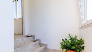 A staircase with stone steps, a potted plant, and a small rug at the bottom.