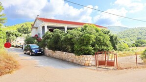 Una casa con tetto rosso, parete in pietra e cancello.