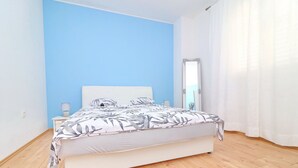 Camera da letto con un letto, un comodino, una lampada e una finestra con tende.