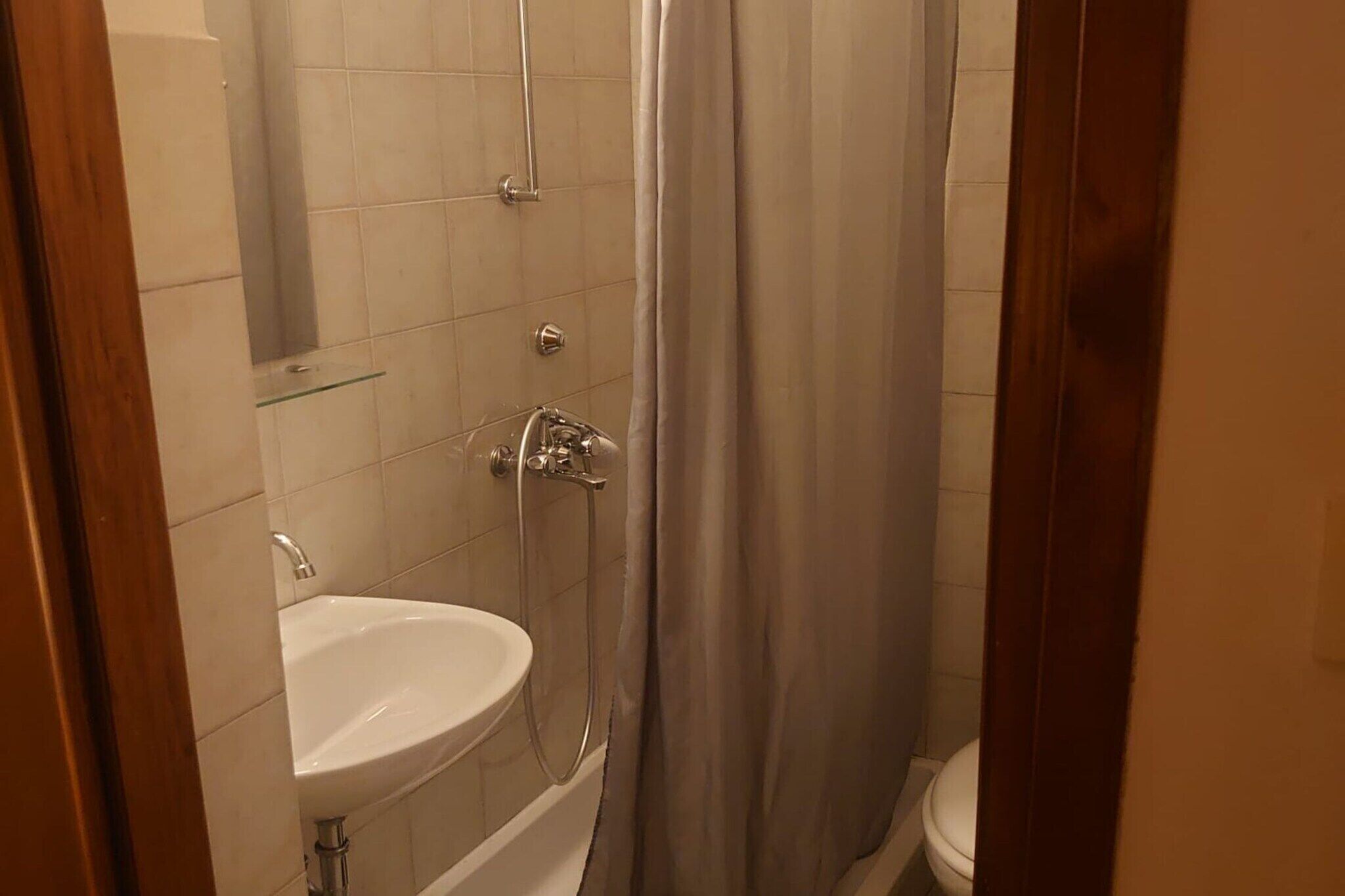 A bathroom with a white sink, a shower with a glass door, and a toilet.