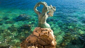 A statue of a woman with a heart shape in her hand, standing on a rock by a clear blue body of water. - Apartments Peselj-Studio Apartment with Balcony and Sea View ( 1 ) (Smokvica)