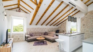 Una cocina moderna con pared de piedra, vigas de madera y una isla grande con pileta y encimera.