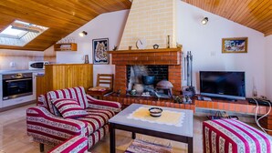 A cozy living room with a fireplace, wooden ceiling, and a TV.