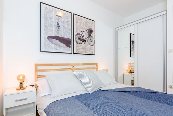 Un dormitorio ordenado con una cama, mesitas de noche y un espejo.