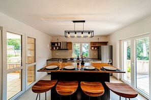Een moderne keuken met een centraal eiland, barstoelen en een eethoek.