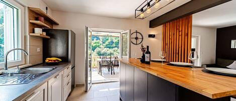 A modern kitchen with a wooden countertop, a built-in oven, and a view to an outdoor dining area.