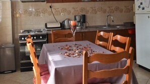 Una cocina con una mesa de comedor dispuesta para cuatro personas, una estufa, un horno y un refrigerador.