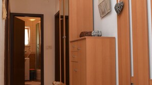 Un pasillo con un armario de madera, una cesta de mimbre y un pequeño cubo de basura.