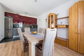 Modern kitchen area with dining table for four, featuring stainless steel appliances and a wooden cabinet.
