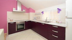 A kitchen with purple cabinets, a white countertop, and a built-in oven.