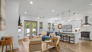 A modern kitchen with white cabinets, stainless steel appliances, and a wooden dining area. - Gone Coastal | Private Pool | 6-Seater Golf Cart | Arcade Games (Watersound)