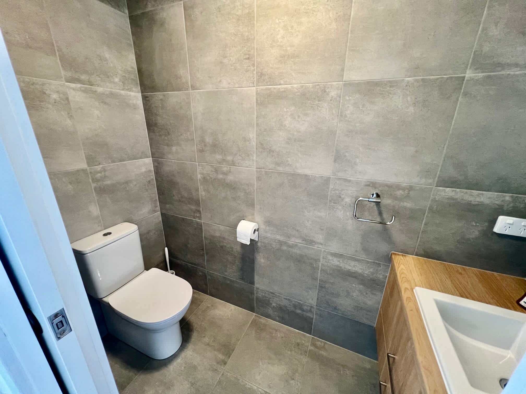 A bathroom with a toilet, a sink, and a shower area.