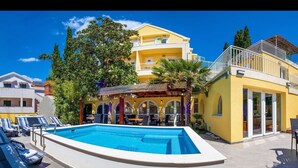 Un hôtel doté d’une piscine, d’un espace extérieur aménagé et dont le bâtiment est de couleur jaune.