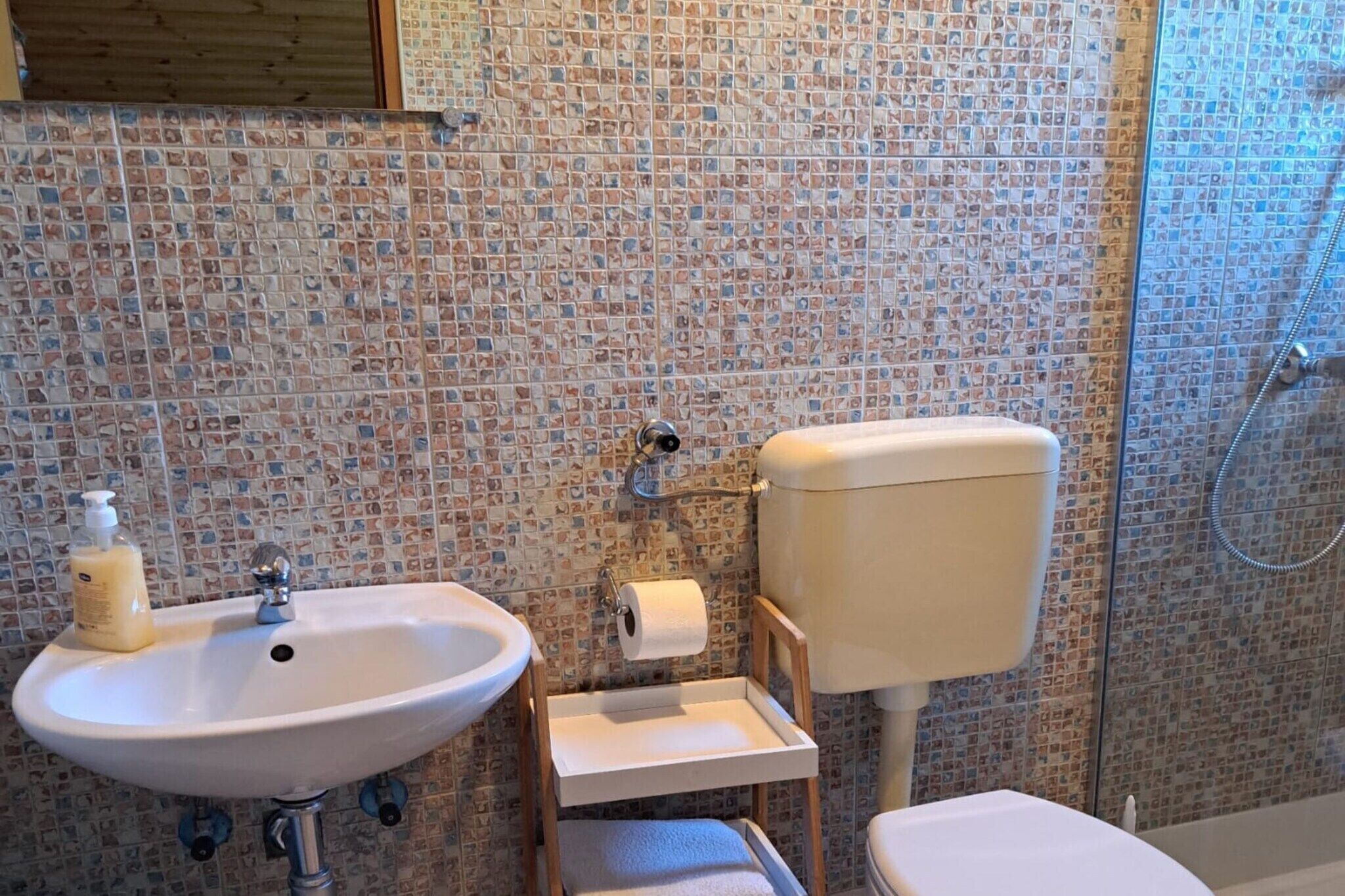 Et badeværelse med vask, toilet og bruser.