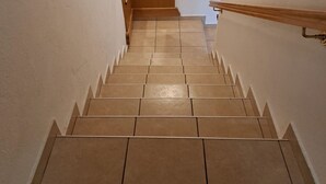A staircase with beige tiles and a wooden handrail. - Guesthouse Žafran- Room With Landscape View (Plitvicka Jezera)