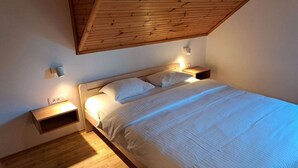 A bedroom with a wooden ceiling, a bed with white bedding, two bedside tables with lamps, and a small shelf unit. - Guesthouse Žafran- Room With Landscape View (Plitvicka Jezera)