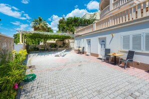 A courtyard with a paved patio, outdoor seating, and a pergola.
