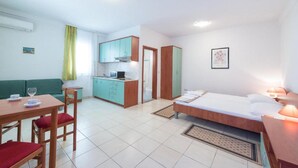Ein kompaktes Hotelzimmer mit Küchenzeile, Essbereich und Bett.