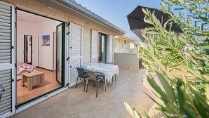 Propiedad residencial con patio que incluye una mesa, sillas, un taburete de madera y una cama con colcha estampada.