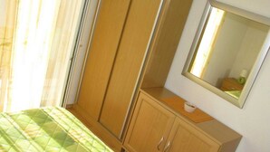 Une chambre à coucher avec un lit, une armoire en bois et un miroir au mur.