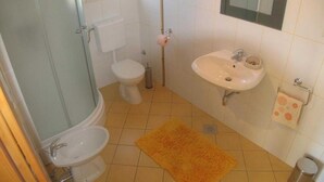 Une salle de bain avec des toilettes, un lavabo et une douche.