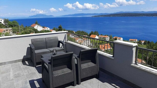 Una terraza con mobiliario de mimbre y vista al mar.