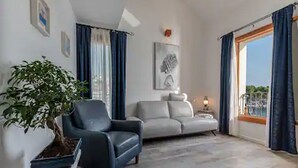 Ein Wohnzimmer mit Sofa, einem Sessel, einem Blumentopf und einem Bild an der Wand.
