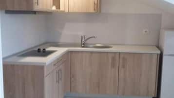 A kitchen with wooden cabinets, a white countertop, and a stainless steel sink.
