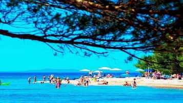 A beach scene with people sunbathing and swimming.