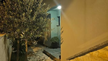 A stone pathway leading to a building entrance with a light fixture above.