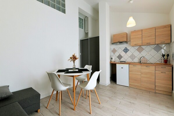 Una cocina moderna con armarios de madera, una encimera blanca y un comedor con mesa y sillas.