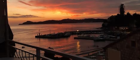 A coastal view with a sunset, marina, and buildings.