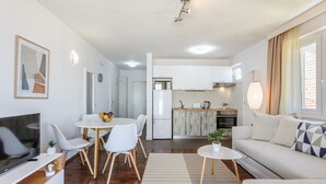 Un salon moderne comprenant un téléviseur, un coin repas, une cuisine et un canapé.