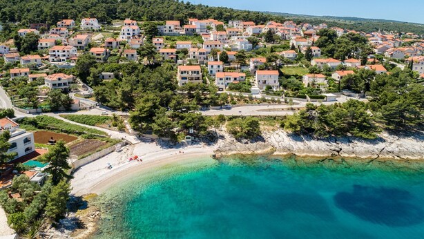 Une ville côtière aux bâtiments blancs, dotée d’une plage et bordée d’eaux turquoise et cristallines.